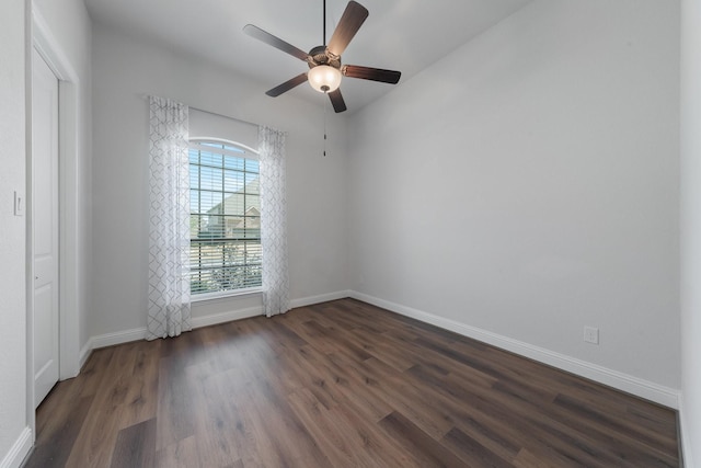 unfurnished room with a ceiling fan, baseboards, and dark wood-type flooring