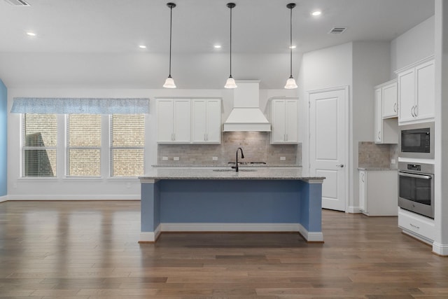 kitchen with black microwave, visible vents, custom exhaust hood, stainless steel oven, and a sink