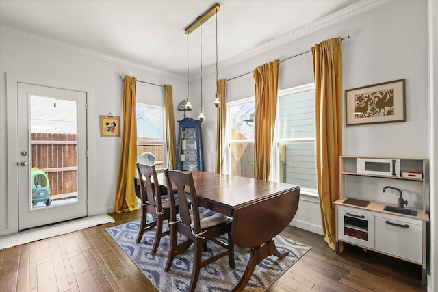 dining area with dark wood-style flooring and crown molding