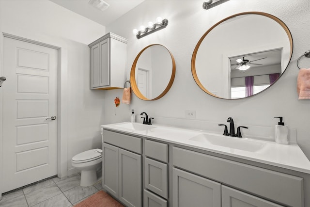 full bath with visible vents, double vanity, a sink, and toilet