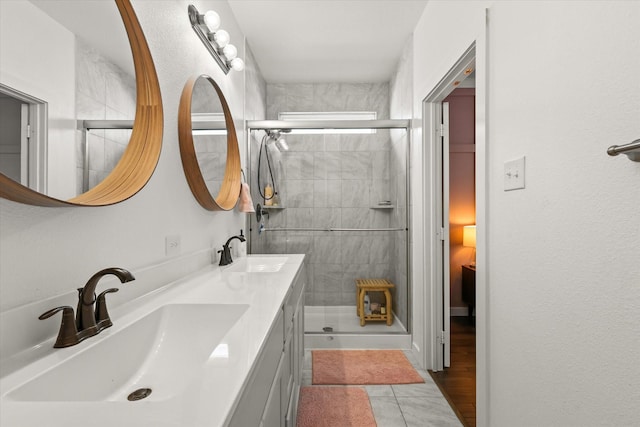 full bath featuring tile patterned floors, a sink, a shower stall, and double vanity