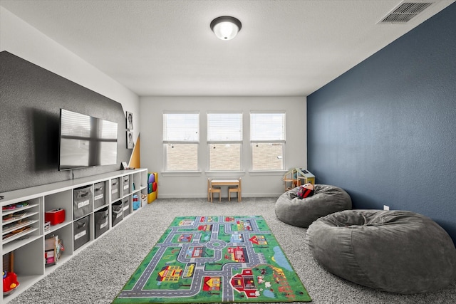 playroom with a textured wall, carpet flooring, visible vents, and baseboards