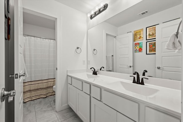 full bath with visible vents, a sink, toilet, and double vanity