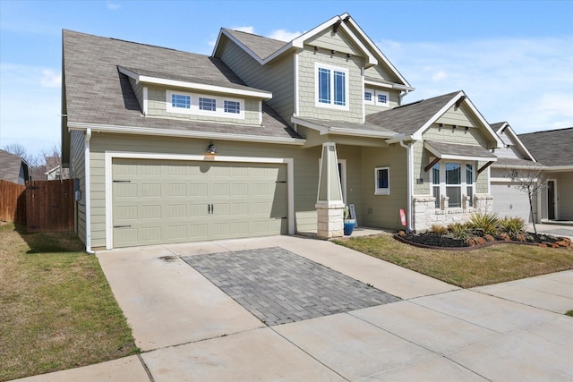 craftsman house featuring concrete driveway, stone siding, an attached garage, fence, and a front lawn