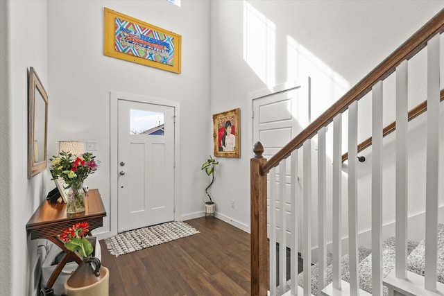 entrance foyer featuring a high ceiling, dark wood-style flooring, stairway, and baseboards