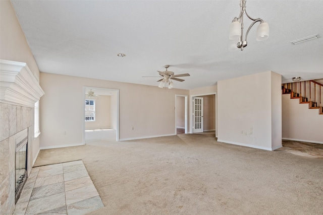 unfurnished living room with carpet, a fireplace, ceiling fan, baseboards, and stairs