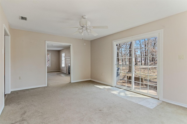 carpeted spare room featuring a fireplace with flush hearth, visible vents, and baseboards