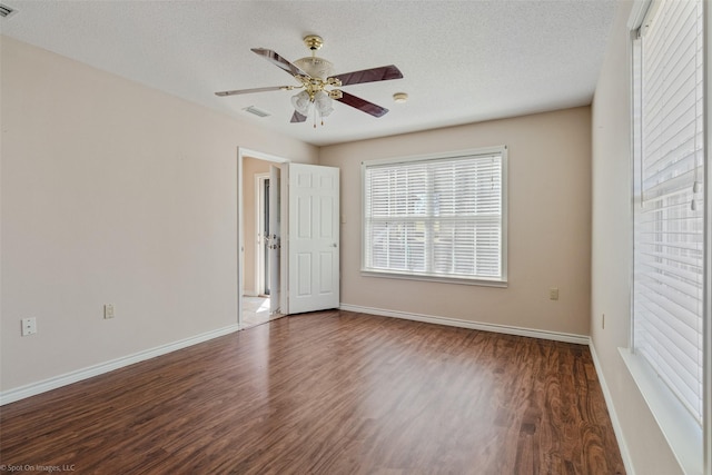 empty room with a textured ceiling, wood finished floors, a ceiling fan, and baseboards