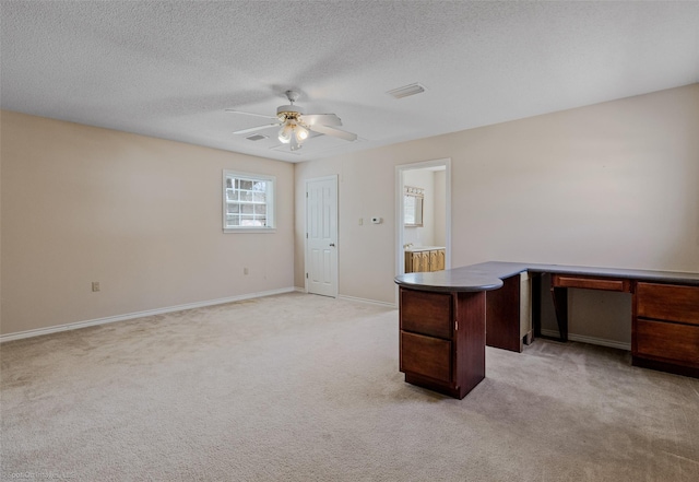 unfurnished office with ceiling fan, a textured ceiling, light colored carpet, visible vents, and baseboards