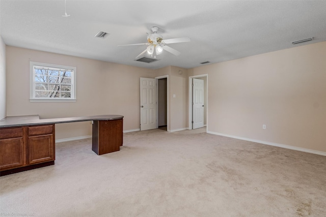 unfurnished office featuring light colored carpet, ceiling fan, visible vents, and baseboards