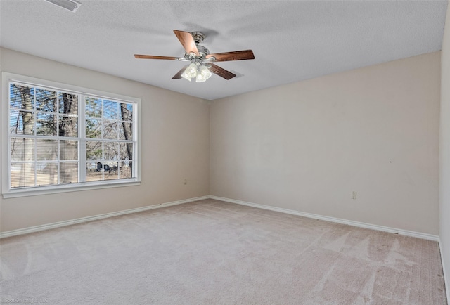 empty room featuring light carpet, ceiling fan, a textured ceiling, and baseboards