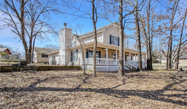 farmhouse inspired home featuring covered porch, a chimney, and fence