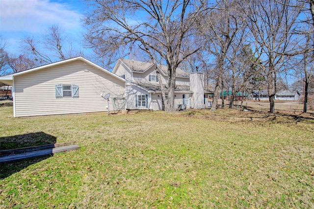 rear view of property with a chimney and a yard