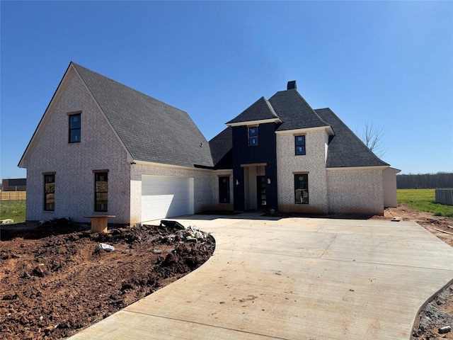 view of front facade with driveway, a garage, and roof with shingles