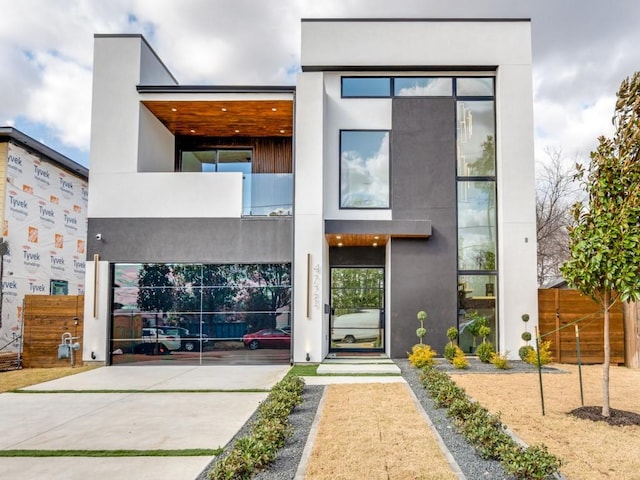 view of front of home with fence, a balcony, and stucco siding