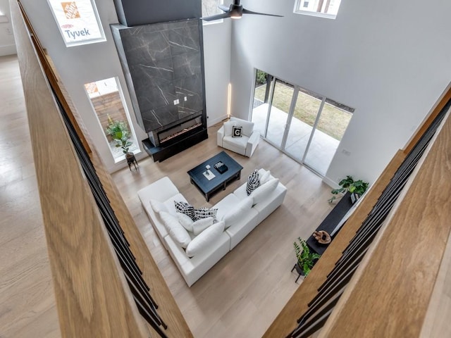 living room with a towering ceiling, plenty of natural light, a ceiling fan, and wood finished floors