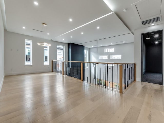 spare room with visible vents, a wealth of natural light, wood finished floors, and attic access