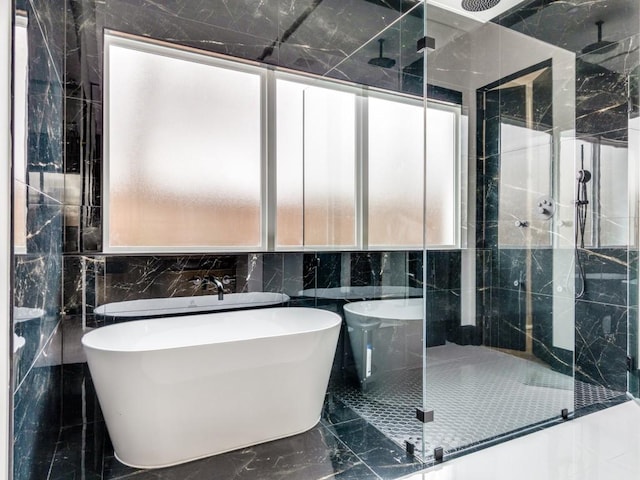 full bathroom featuring a stall shower, marble finish floor, and a freestanding tub