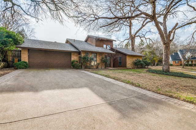 mid-century home with a garage, driveway, and brick siding