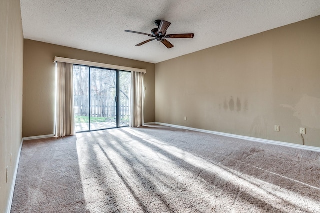 carpeted empty room with ceiling fan, a textured ceiling, and baseboards