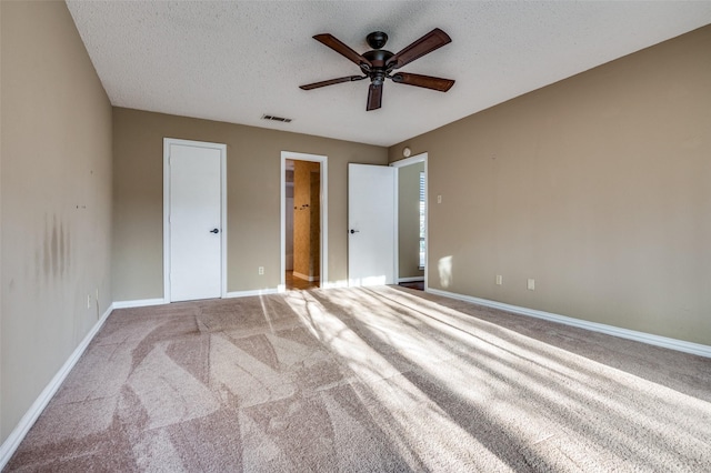 unfurnished bedroom featuring a textured ceiling, carpet floors, visible vents, and baseboards