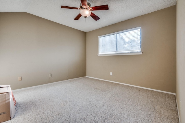 spare room with carpet, vaulted ceiling, a textured ceiling, ceiling fan, and baseboards