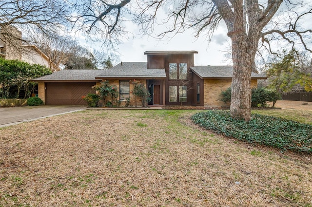 view of front of house with an attached garage, driveway, a front yard, and brick siding