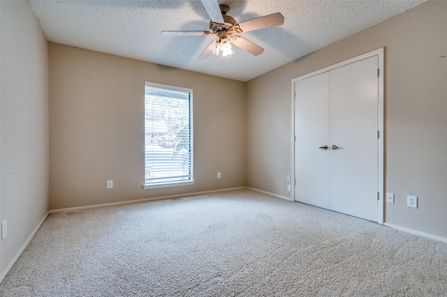 unfurnished bedroom with carpet floors, a closet, ceiling fan, a textured ceiling, and baseboards