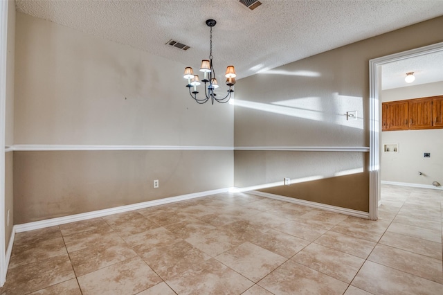 tiled spare room featuring a chandelier, a textured ceiling, visible vents, and baseboards