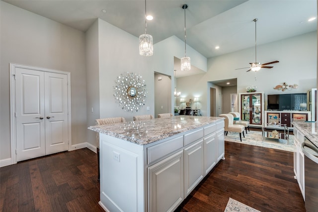 kitchen with light stone counters, dark wood-style flooring, a kitchen island, white cabinetry, and open floor plan