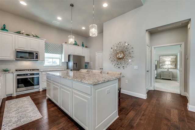 kitchen featuring appliances with stainless steel finishes, dark wood-style flooring, white cabinetry, and a center island