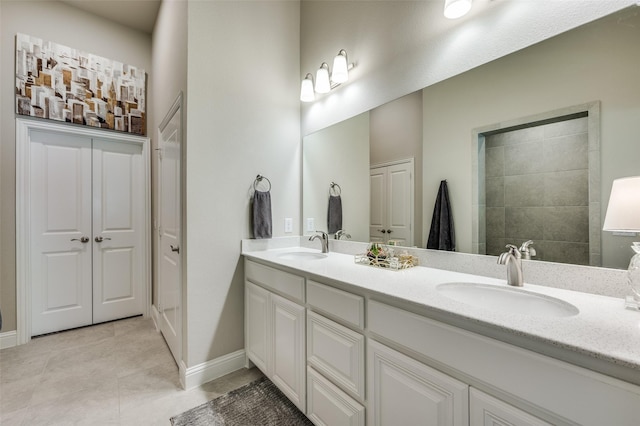 full bath with double vanity, baseboards, a sink, and tile patterned floors