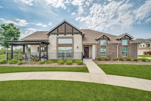 view of front of property featuring brick siding, fence, stone siding, roof with shingles, and a front lawn