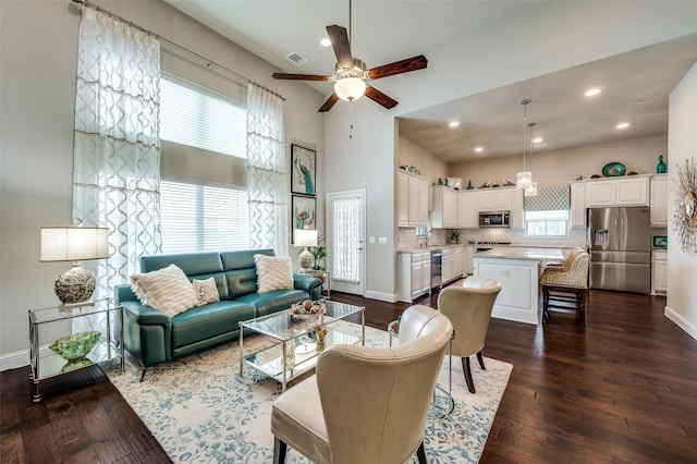 living area featuring visible vents, a high ceiling, baseboards, and dark wood finished floors