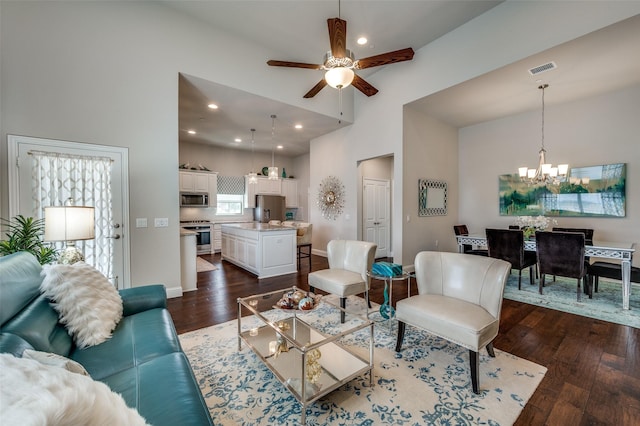 living area featuring dark wood-style floors, visible vents, high vaulted ceiling, and ceiling fan with notable chandelier