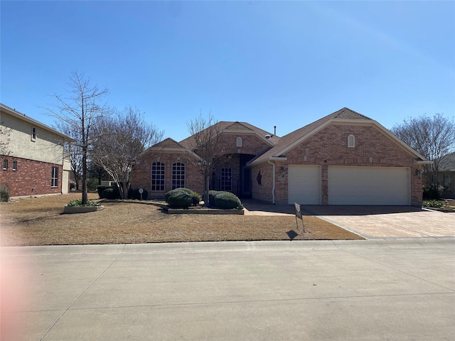 view of front of home with a garage, concrete driveway, and brick siding