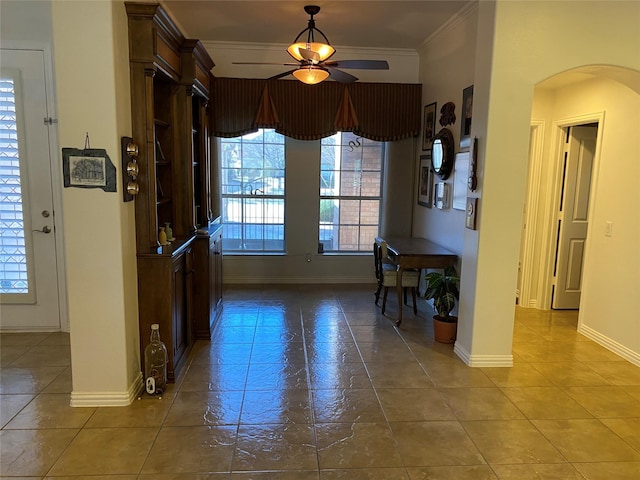 foyer entrance featuring plenty of natural light, arched walkways, ceiling fan, and crown molding