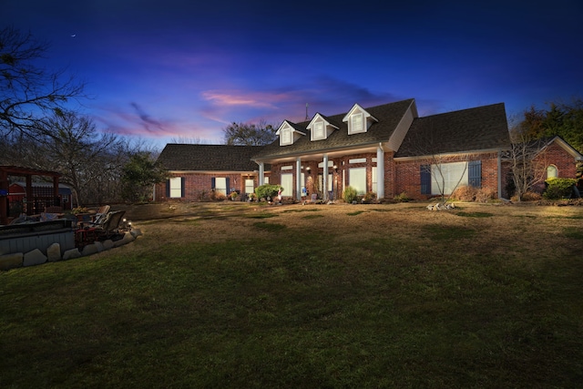 cape cod home with a front lawn and brick siding