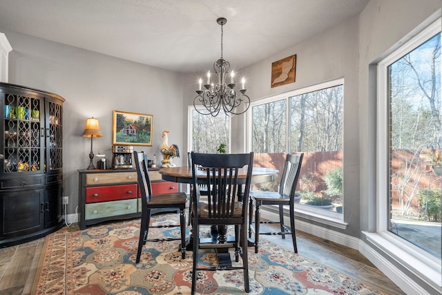 dining area featuring wood finished floors, a wealth of natural light, and a notable chandelier