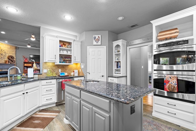 kitchen with stainless steel appliances, visible vents, a sink, and open shelves