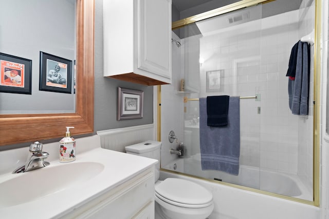 bathroom with shower / bath combination with glass door, visible vents, toilet, wainscoting, and vanity