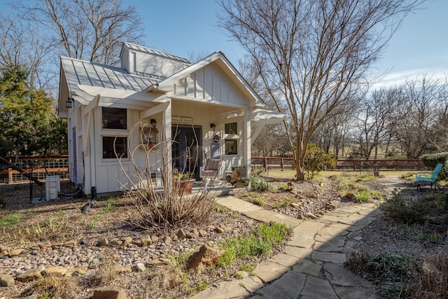 bungalow-style house with a standing seam roof, fence, metal roof, and board and batten siding