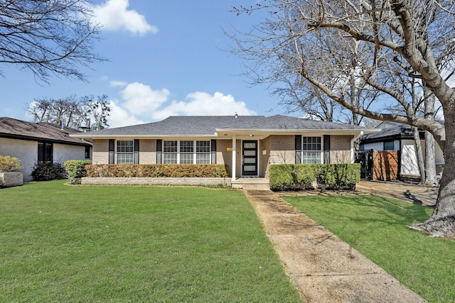 single story home with a shingled roof, fence, a front lawn, and brick siding