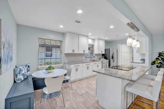 kitchen featuring a center island, stainless steel appliances, visible vents, decorative backsplash, and a sink