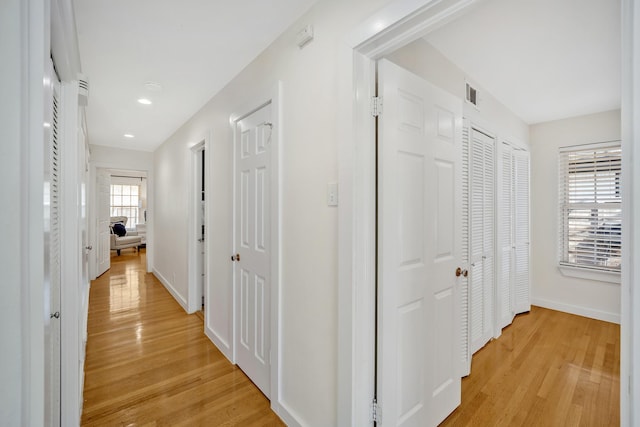 hallway with light wood-type flooring, visible vents, baseboards, and recessed lighting