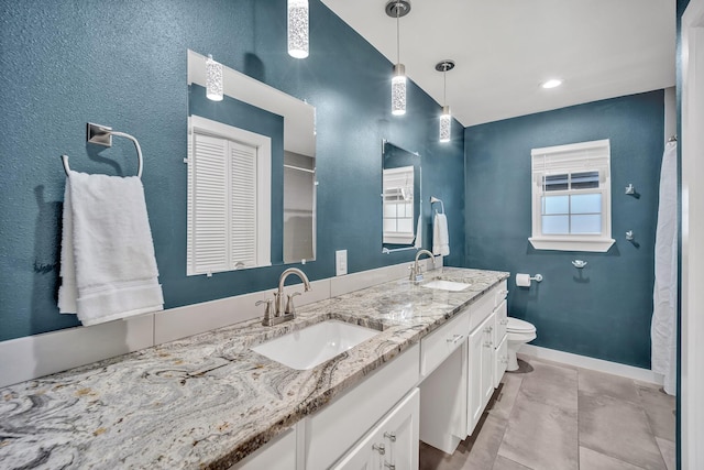 full bathroom with toilet, double vanity, baseboards, and a sink