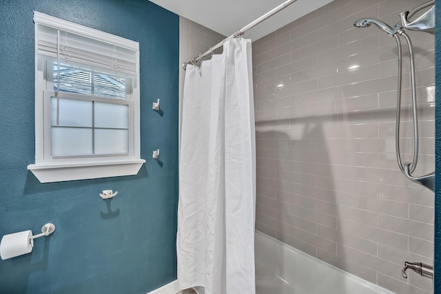 full bathroom featuring a textured wall and shower / bath combo