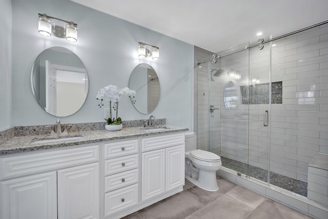 full bathroom with double vanity, a sink, toilet, and a shower stall