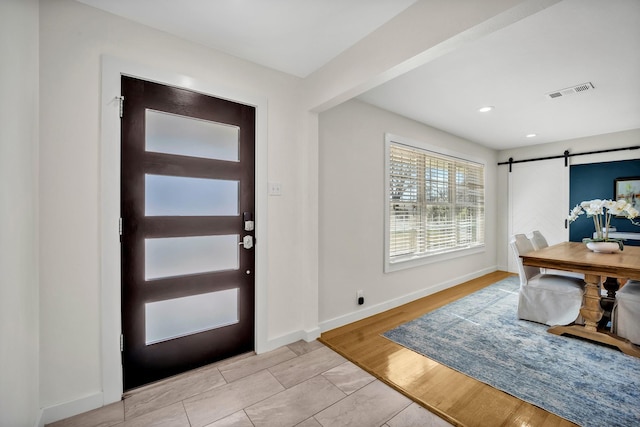 entryway featuring light wood finished floors, recessed lighting, visible vents, a barn door, and baseboards