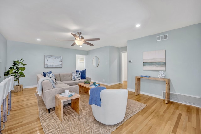 living room featuring a ceiling fan, wood finished floors, visible vents, and baseboards